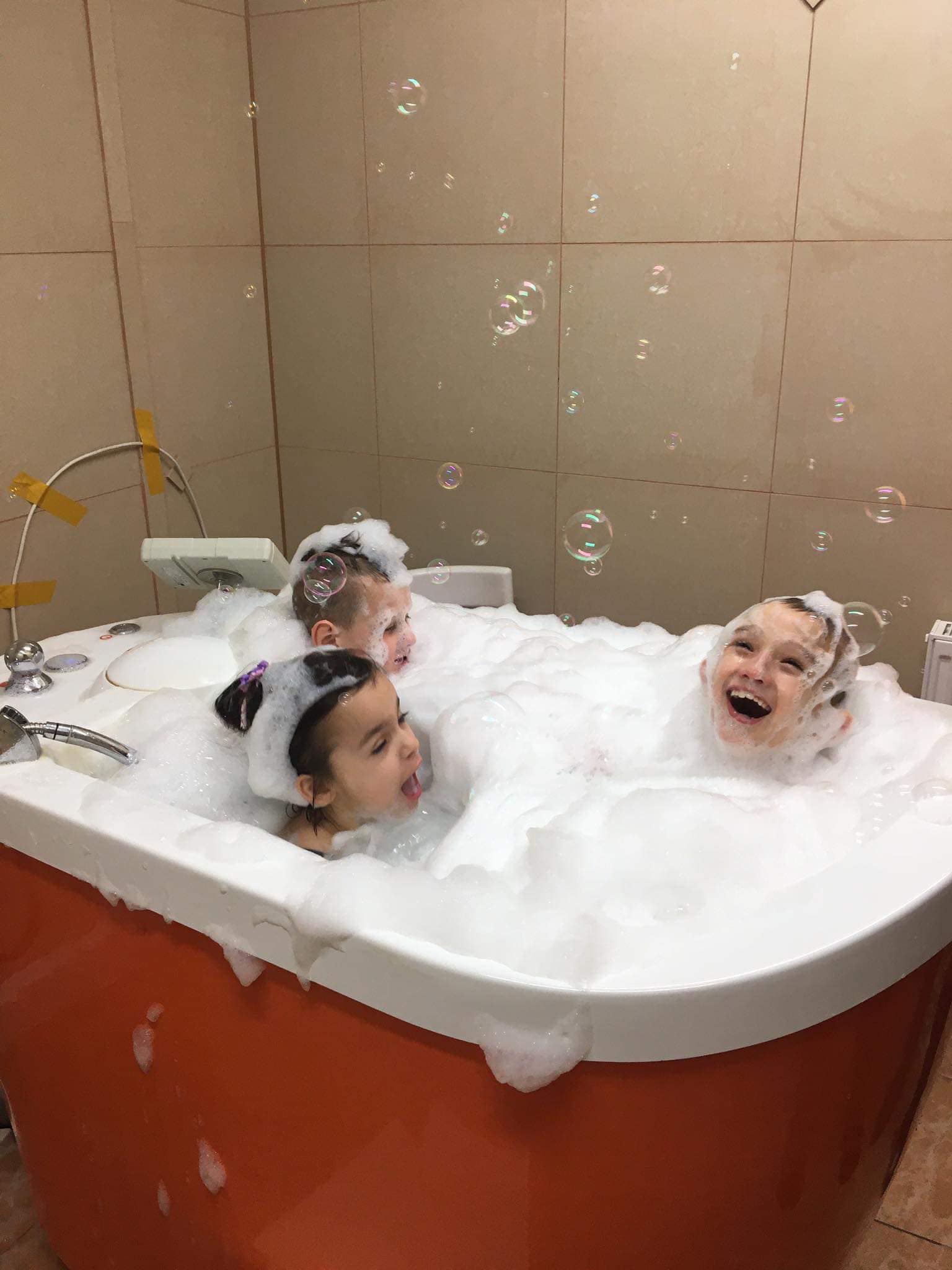 Dzieci kąpią się w wannie pełnej piany aby uczcić dzień piany, sprawia im to bardzo dużo radości